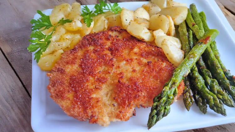 German schnitzel recipe served with roasted asparagus and fried potatoes