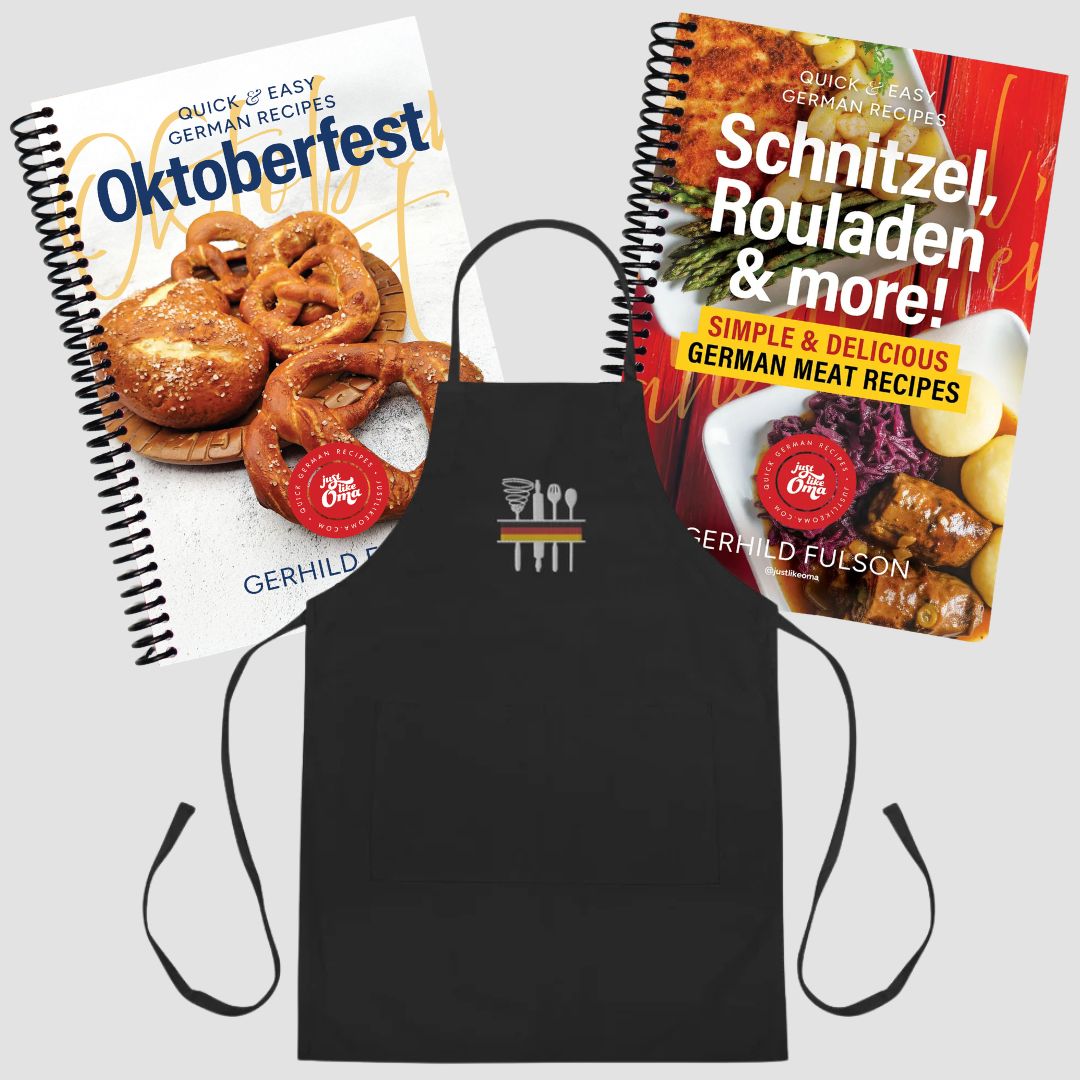 A black apron with a small white and red logo in the center, displayed with two spiral-bound recipe books titled Oktoberfest and Schnitzel, Rouladen & more! on a light gray background.