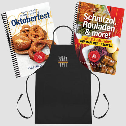 A black apron with a small white and red logo in the center, displayed with two spiral-bound recipe books titled Oktoberfest and Schnitzel, Rouladen & more! on a light gray background.